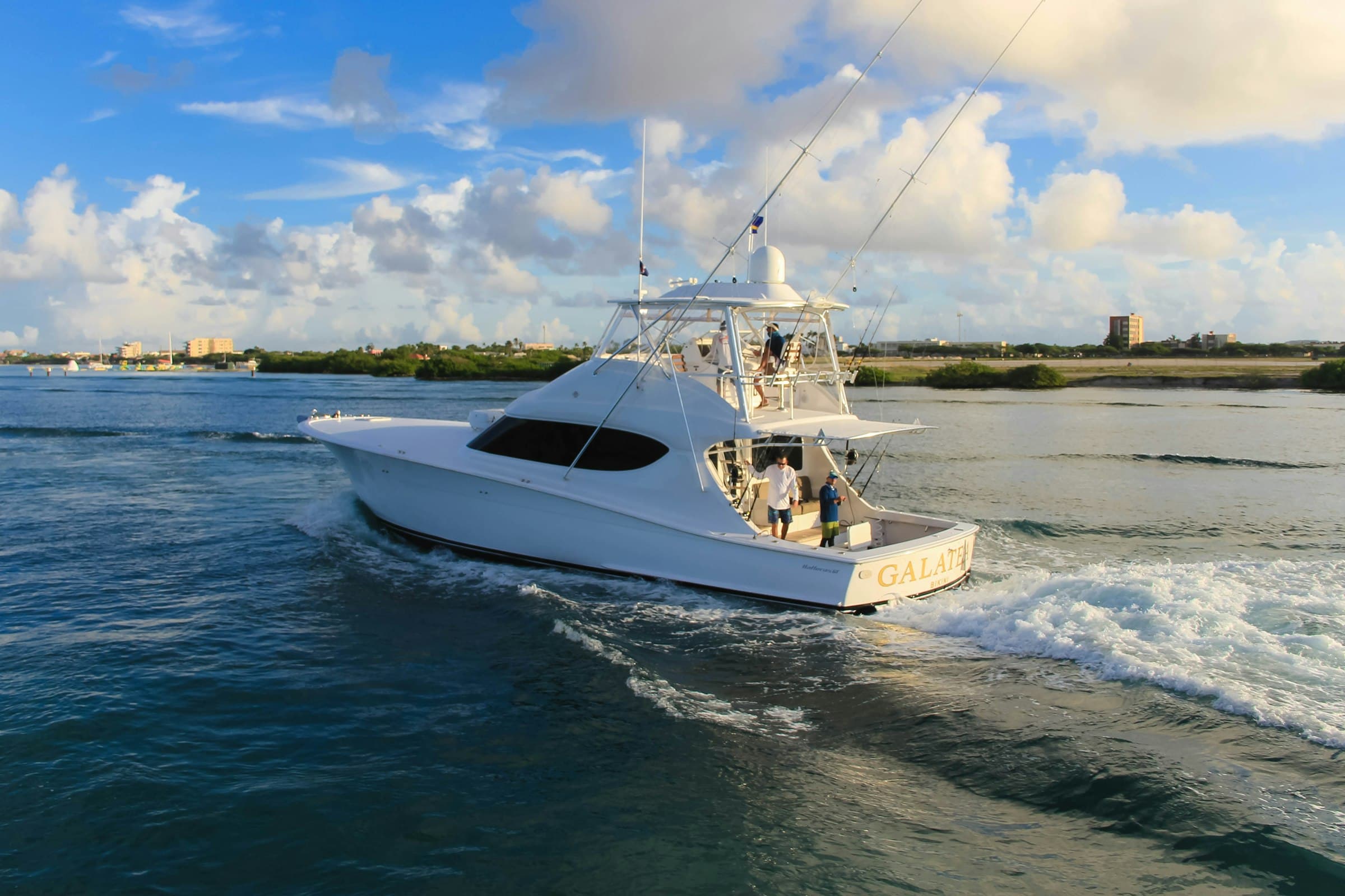 Sportfishing boat with tuna tower and outriggers heading out over blue water at golden hour